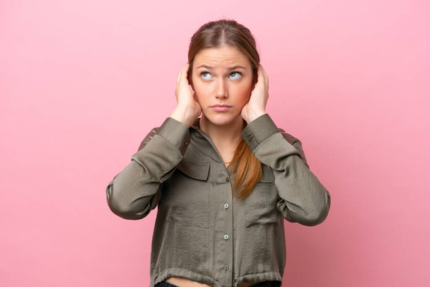 Mladá běloška žena izolované na růžovém pozadí frustrované a zakrývající uši - Fotografie, Obrázek