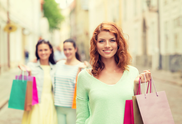 niñas adolescentes sonrientes con bolsas de compras en la calle
 - Foto, Imagen