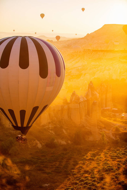 Gorgeous sunrise scenery of hot air balloons flying over Love valley with rock formations and fairy chimneys in Cappadocia Turkey - 写真・画像