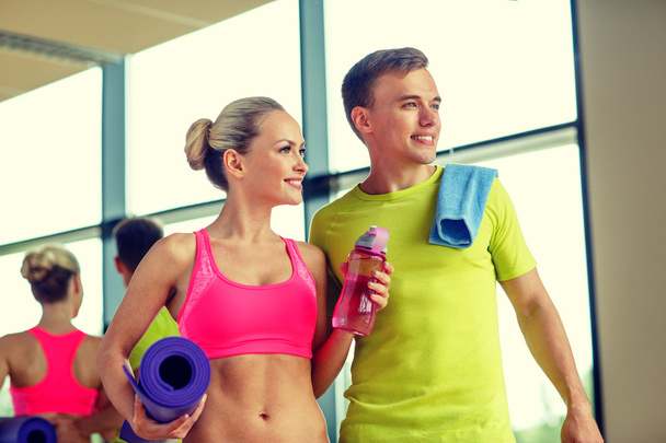 smiling couple with water bottles in gym - Foto, Imagen
