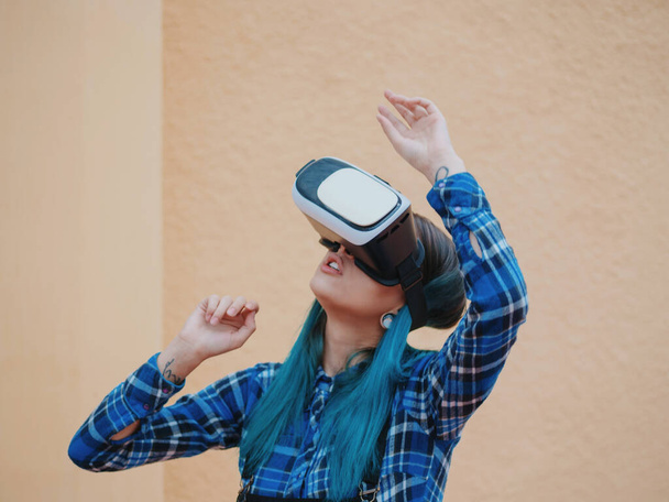 Street punk or hipster girl with blue dyed hair having fun with vr glasses. Carefree concept. Virtual reality concept. Slow motion. - Φωτογραφία, εικόνα