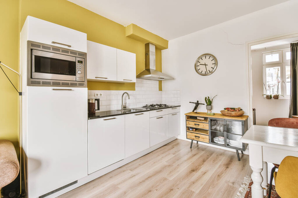 Töredéke belső világos keskeny konyha minimalista stílusú fehér bútorok mosogató és tűzhely - Fotó, kép