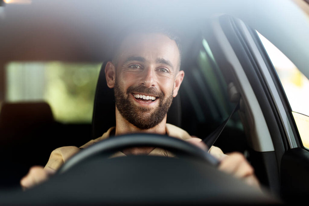 Handsome smiling latin man driving a car. Transportation, car sharing concept  - Fotó, kép