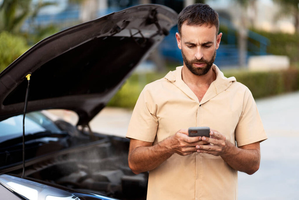 Worried man driver calling car service, having engine problem standing near broken car on the road. Car breakdown concept - Photo, Image