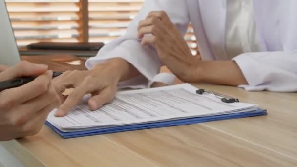 Young patient woman consulting doctor with for filling document contract about insurance and signing at clinic, physician explaining and advice patient form paperwork, signature and medical concept. - Footage, Video