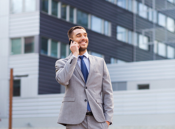 hombre de negocios sonriente con teléfono inteligente al aire libre
 - Foto, Imagen