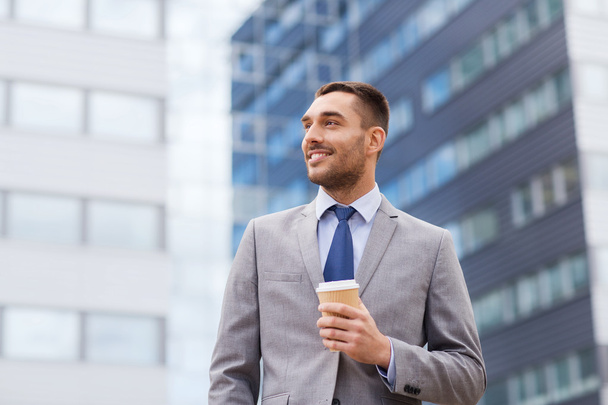 young smiling businessman with paper cup outdoors - Foto, afbeelding