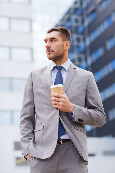 young serious businessman with paper cup outdoors - Photo, Image