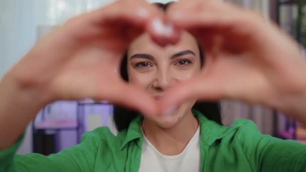 I love you. Romantic girl makes symbol of love, showing heart sign to camera, express feelings, express sincere positive good feelings. Charity, gratitude, donation. Young woman close-up happy face - Záběry, video