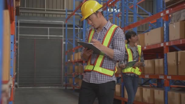 Young man and woman worker check stock and inspection with document on clipboard in the warehouse at factory, worker working at storehouse, logistic and cargo, shipping and distribution. - Footage, Video