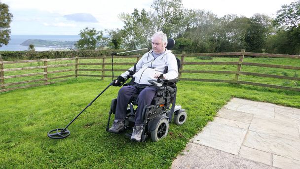 Vammainen mies Pyörätuolin käyttäjä metalli havaitsee kolikoiden alalla - Valokuva, kuva