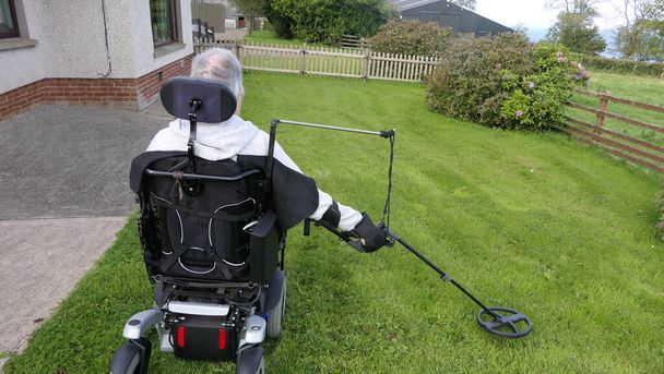 Niepełnosprawny mężczyzna Użytkownik wózka inwalidzkiego metal wykrywający monety na polu - Zdjęcie, obraz