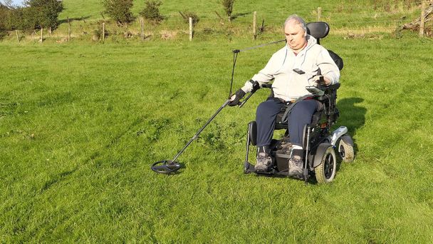 Homem com deficiência Cadeira de rodas metal usuário detecção de moedas em um campo - Foto, Imagem