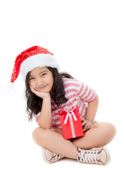 Маленькая азиатская девочка в шляпе Санты и красная коробка подарков изолированы на белом
 - Фото, изображение