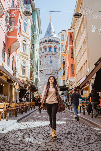 woman walking through an alley full with cafe and historical building in istanbul turkey - Photo, Image
