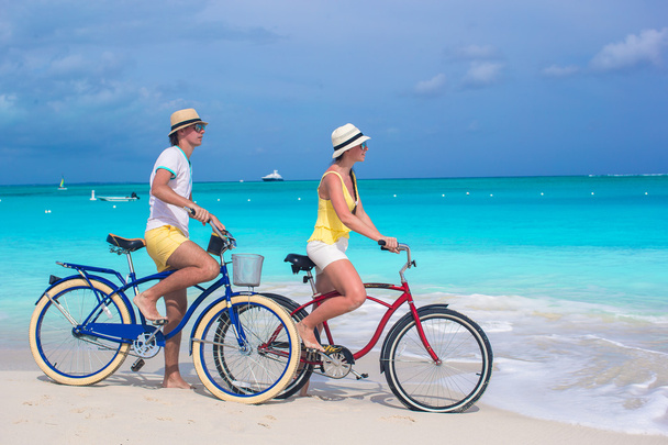 Young happy couple riding bikes on white tropical beach - Photo, Image