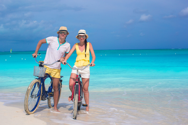 Jovem casal feliz andar de bicicleta na praia tropical branca
 - Foto, Imagem