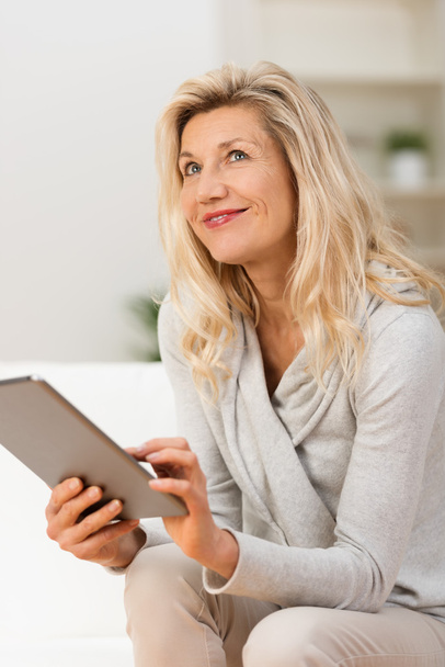 Woman using tablet sitting thinking - Foto, afbeelding