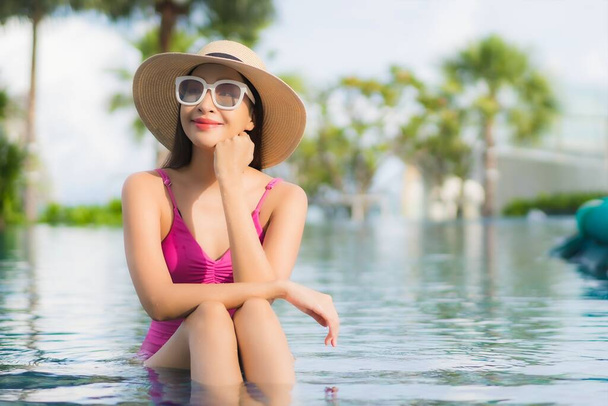 Retrato hermosa joven mujer asiática relajarse disfrutar alrededor de la piscina al aire libre en vacaciones - Foto, imagen