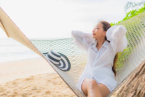 Portré gyönyörű fiatal ázsiai nő pihenni függőágyon körül strand tenger óceán szabadidős nyaralás - Fotó, kép