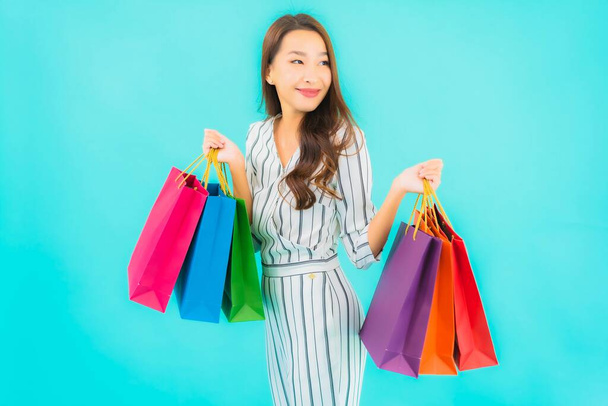 Porträt schöne junge asiatische Frau mit farbiger Einkaufstasche auf blauem Hintergrund - Foto, Bild