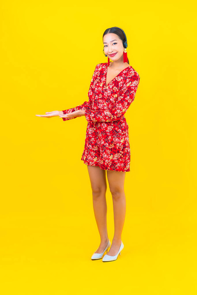 Ritratto bella giovane donna asiatica con auricolare per cliente call center cura su sfondo giallo - Foto, immagini