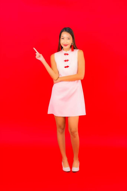 Retrato hermosa joven mujer asiática desgaste chino nuevo año ropa sobre fondo rojo - Foto, Imagen