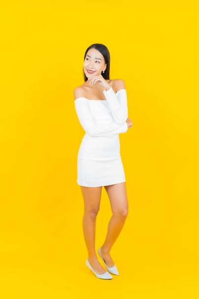 Portrait beautiful young business asian woman with smile and action yellow background - Fotó, kép