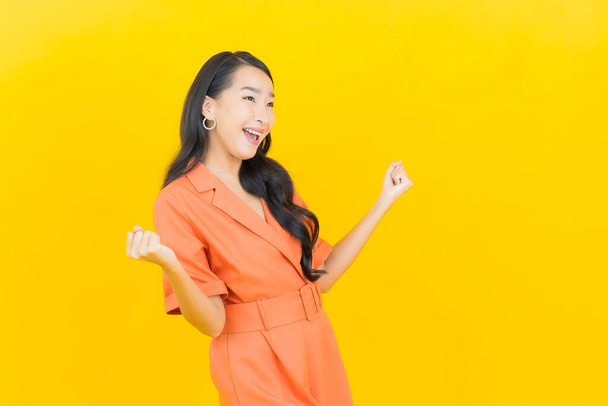 Porträt schöne junge asiatische Frau lächeln mit Aktion auf gelbem Hintergrund - Foto, Bild