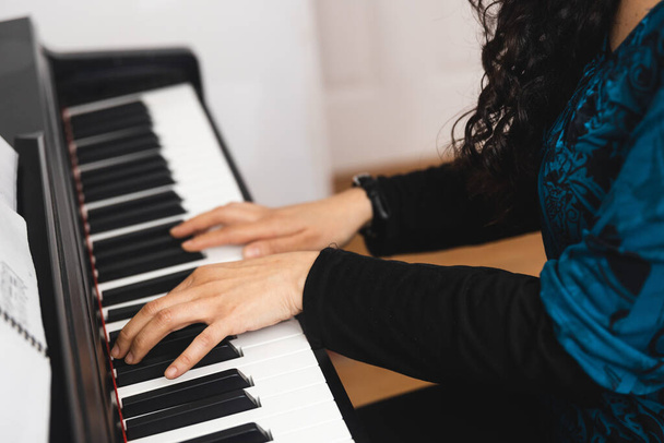 Close up of womans hands playing piano by reading sheet music. High quality photo - Foto, Imagen