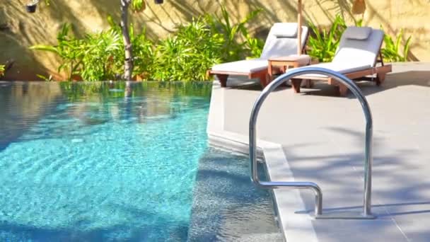 Lettini intorno alla piscina all'aperto in hotel resort per vacanze di viaggio - Filmati, video