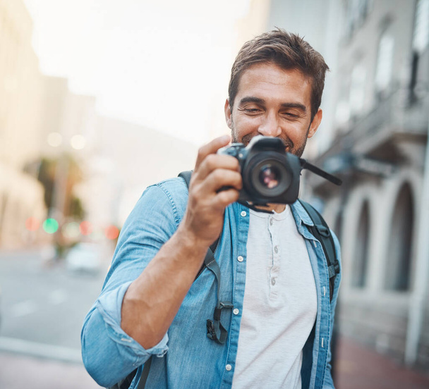 Photography makes you more aware of your surroundings. a young man taking photos while exploring a foreign city - Foto, imagen