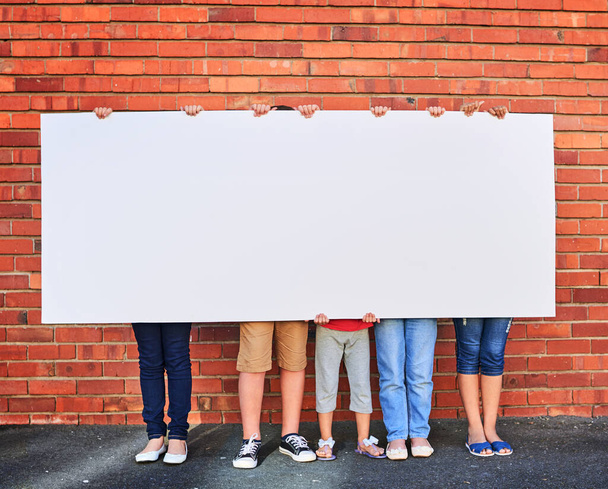 Weve saved this space for you. a group of young children holding a blank sign against a brick wall - Fotoğraf, Görsel