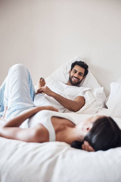 Lets laze in bed all day. a young couple lying on a bed together at home - Foto, imagen