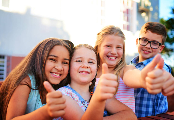 We think youre awesome. Portrait of a group of young children showing thumbs up outside - Foto, Bild