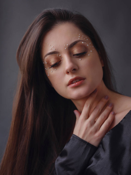 Beauty, fashion studio portrait of young woman in black dress with pearl makeup. Aesthetics of minimalism. Concept for spa, wedding salons, beauty treatments. - Foto, imagen