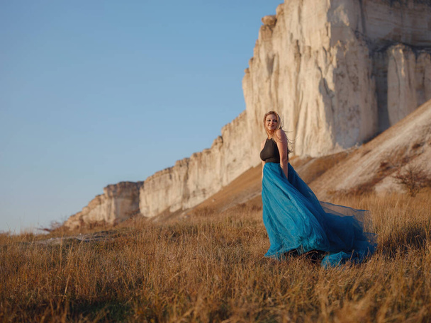 Muodikas nainen autiomaassa lähellä vuorta yllään musta toppi ja sininen tylli hame. Villi länsi Kesäjuhlatanssit. Kaunis ja seksikäs plus koko malli - Valokuva, kuva