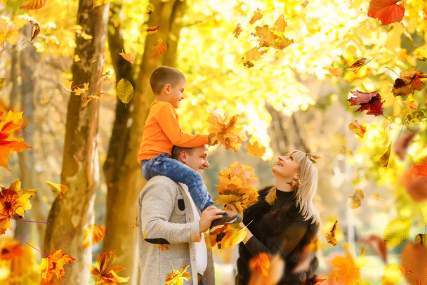 family, childhood, season and people concept - happy family playing with autumn leaves in park. High quality photo - 写真・画像