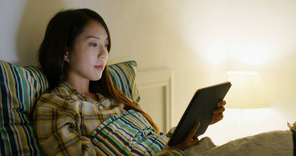 Woman read on tablet computer on bed at night - Foto, Imagen