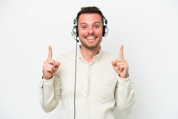 Telemarketer caucasian man working with a headset isolated on white background pointing up a great idea - Foto, afbeelding