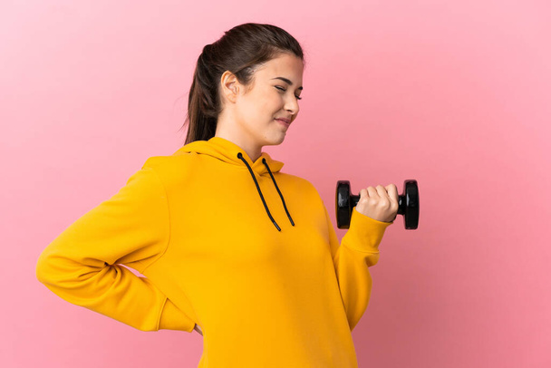 Young sport girl making weightlifting over isolated pink background suffering from backache for having made an effort - Foto, imagen