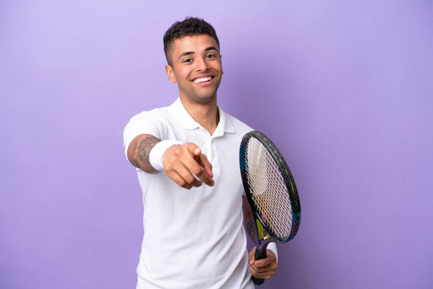 Young Brazilian man isolated on purple background playing tennis and pointing to the front - Foto, Imagem
