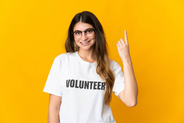 Young volunteer woman isolated on yellow background pointing up a great idea - Foto, immagini