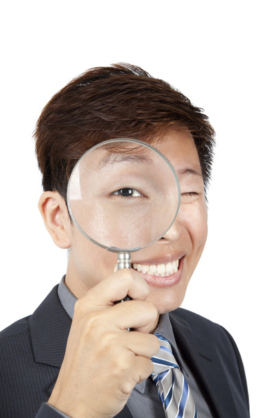 Азиатский бизнесмен держит лупу над глазом
 - Фото, изображение