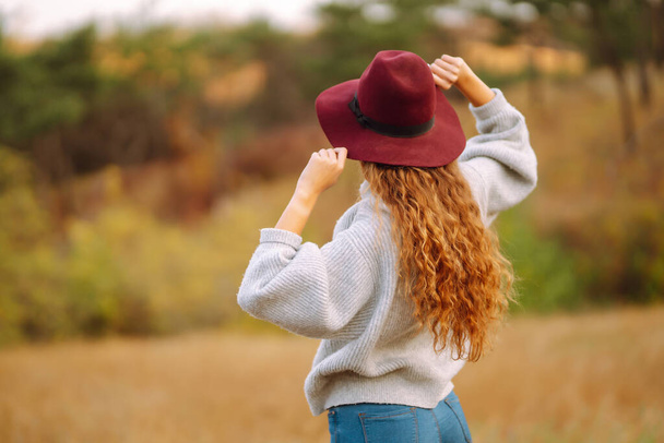 Stylish woman  in hat enjoying autumn weather in the park. Fashion, style concept. - 写真・画像