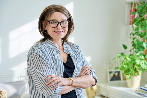 Portrait of confident mature woman looking at camera at home. Middle aged smiling successful female in glasses with crossed arms. 40s age, lifestyle, people concept - Foto, Imagem