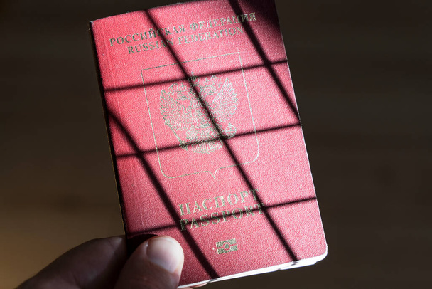 Russian foreign passport in the hands of a man. Prohibition of Schengen visas for Russian tourists to travel to the European Union concept. High quality photo - Foto, Imagen