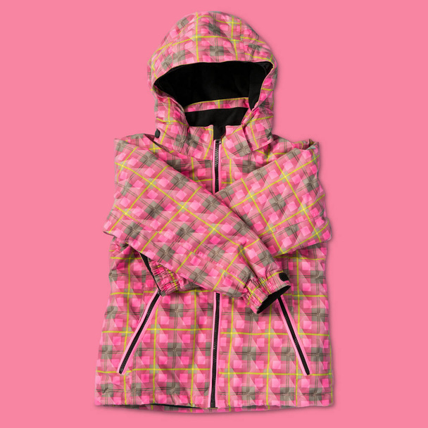 розовая женская зимняя куртка из ткани плаща, на розовом фоне, концепция - Фото, изображение