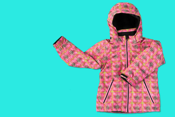 pink women's winter jacket, on a turquoise background, the sleeves seem to show gestures, the concept of seasonal shopping - Photo, Image
