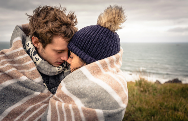 Young couple embracing outdoors under blanket in a cold day - Photo, Image